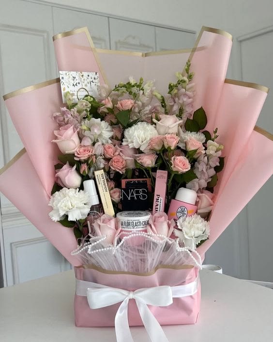 Pink floral gift arrangement containing beauty products