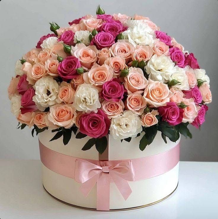 Pink, peach and white flowers arranged in a round hat box